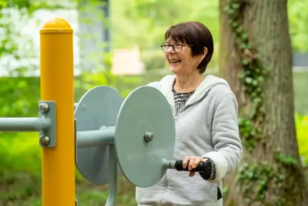 Femme senior utilisant un moulinet de matériel de fitness extérieur