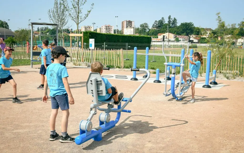 Enfants pratiquant le fitness en plein air sur des équipements extérieurs. Dynamisation de la vie étudiante par le sport en extérieur.