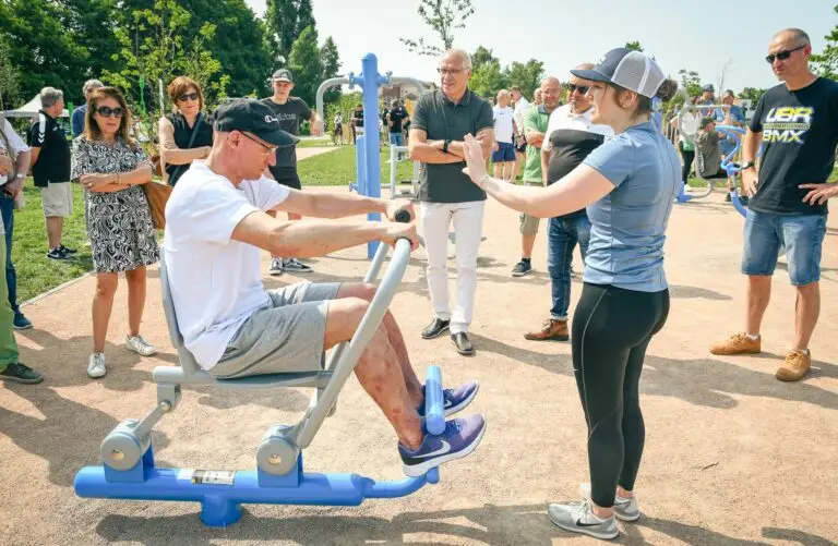 Adulte pratiquant le fitness en plein air sur des équipements extérieurs. Dynamisation de la vie étudiante par le sport en extérieur.