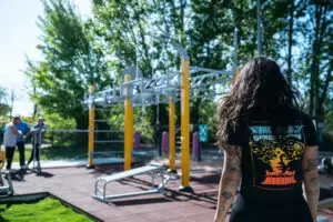 Femme devant des équipements de street-workout extérieur jaune et gris