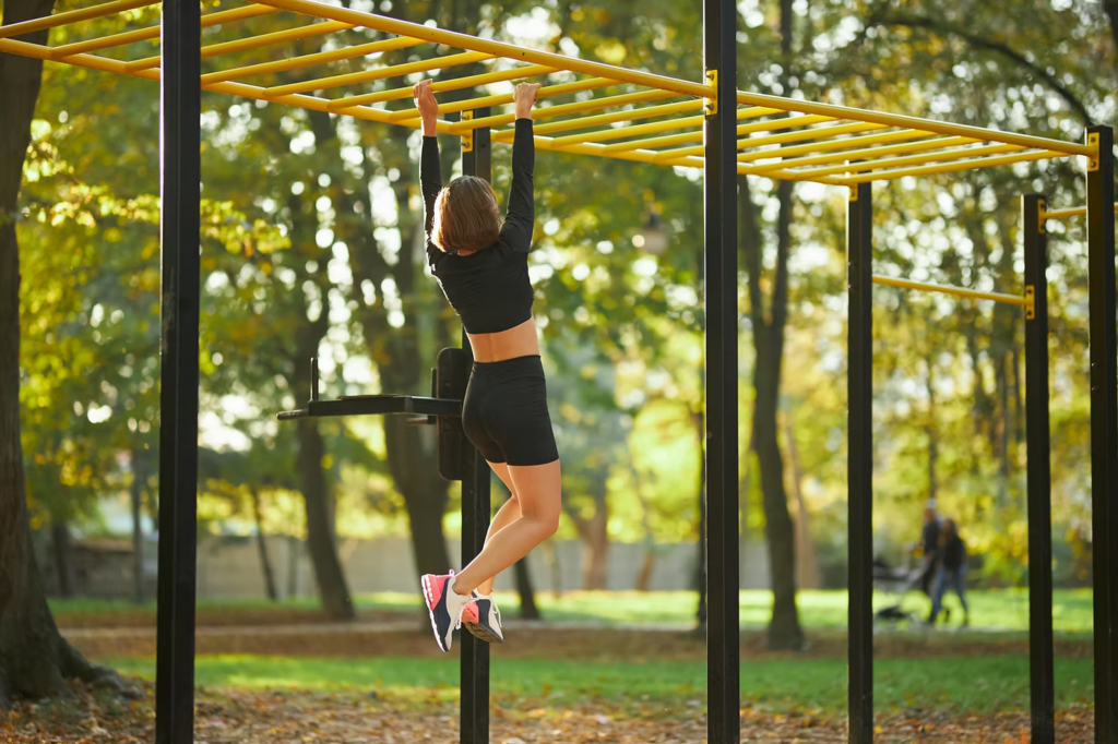 Femme pratiquant le street workout sur des barres parallèles en extérieur. Illustration de l'essor du street workout féminin.