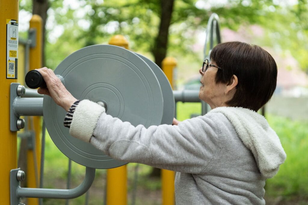 Séniore utilisant un équipement de fitness extérieur pour améliorer son équilibre et sa mobilité. Illustration des bienfaits du fitness extérieur pour les séniors.