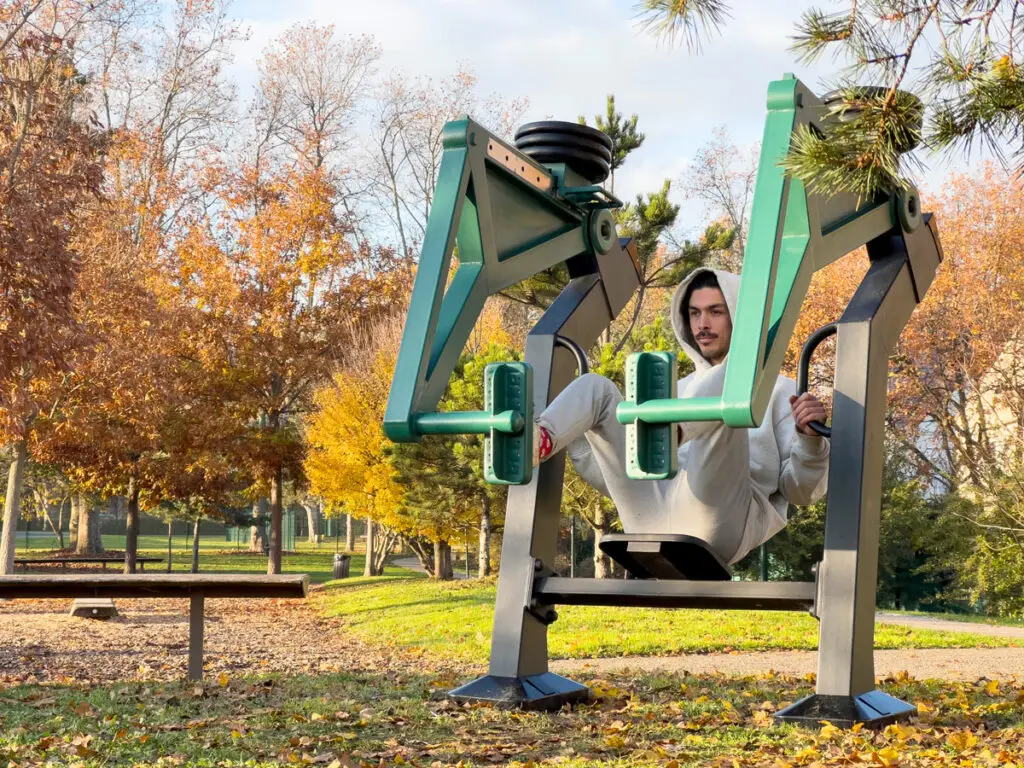 Aire de fitness d'extérieur conforme aux normes de sécurité avec équipement de musculation leg press. Aménagement sécurisé pour entraînement en plein air.